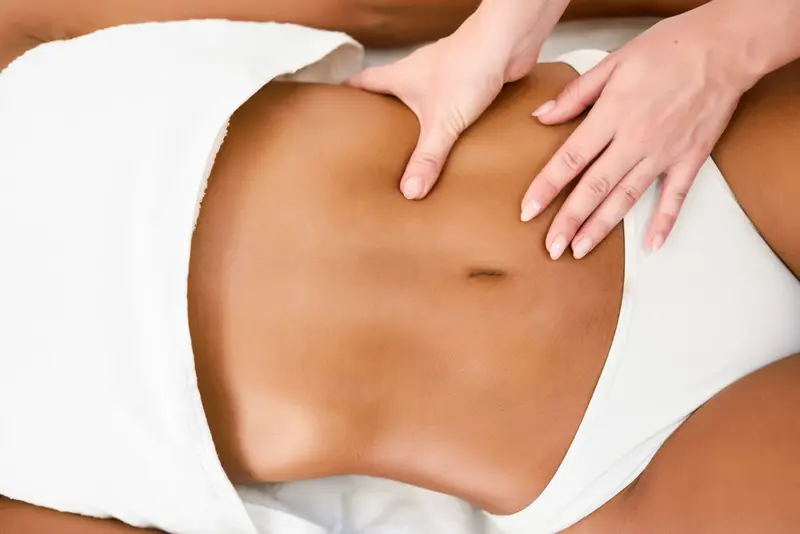 Mains posées sur le ventre pendant une séance de drainage lymphatique